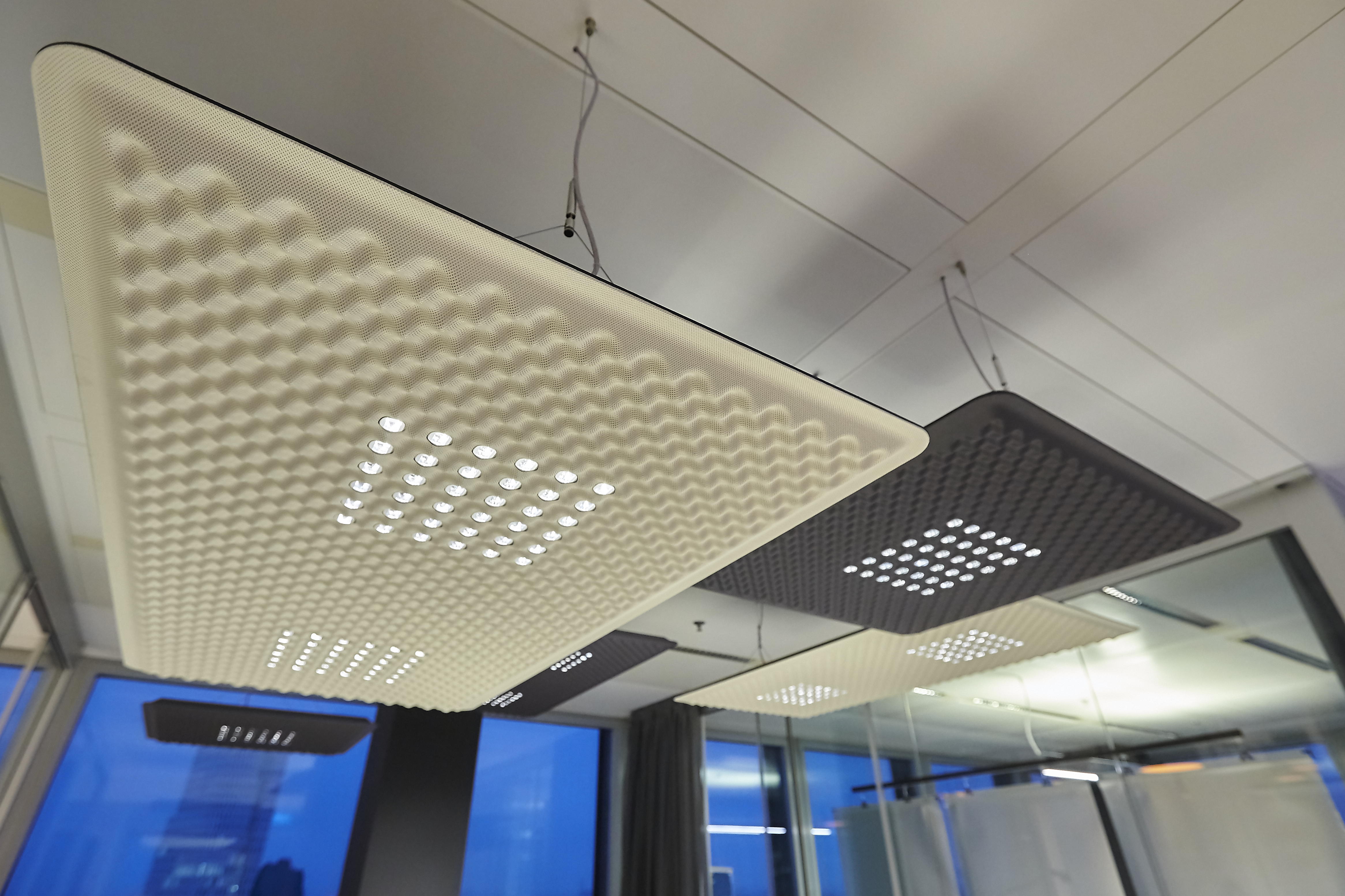 Moderne Akustikdeckenleuchten in Weiß und Anthrazit mit LED-Beleuchtung für Büro und Konferenzraum.