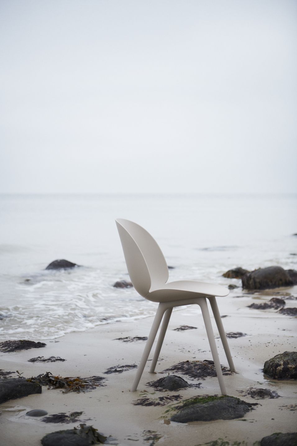 Beige Beetle Chair Outdoor Esszimmerstuhl von Gubi am Strand, Meer im Hintergrund.