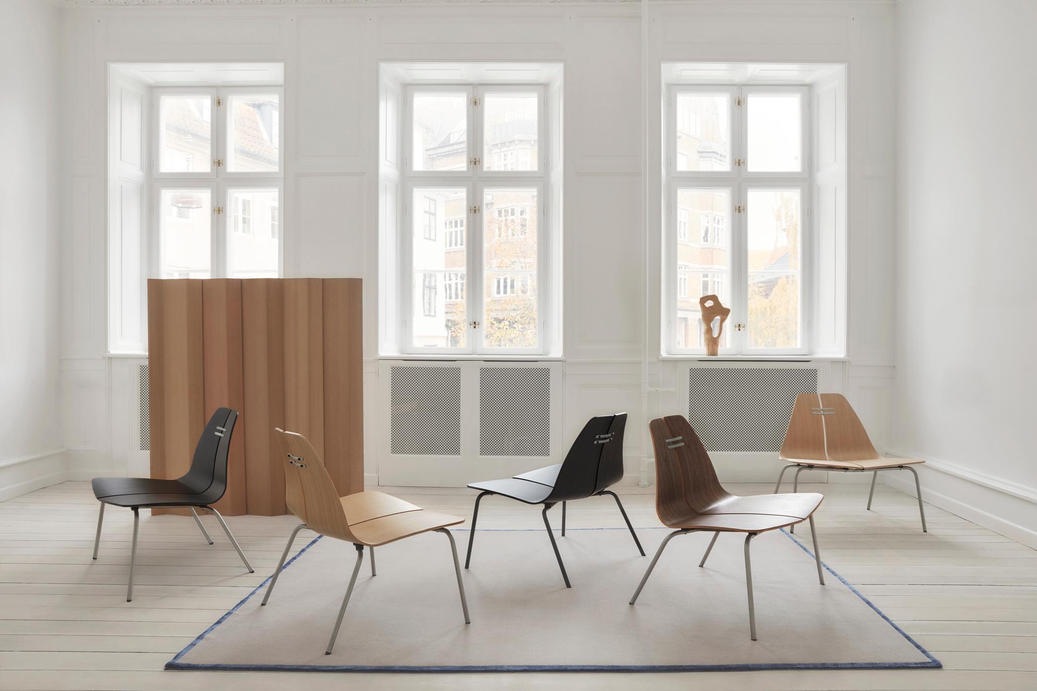 Fünf Fritz Hansen PK23 Loungesessel aus Holz und Metall in verschiedenen Farben im hellen Raum.