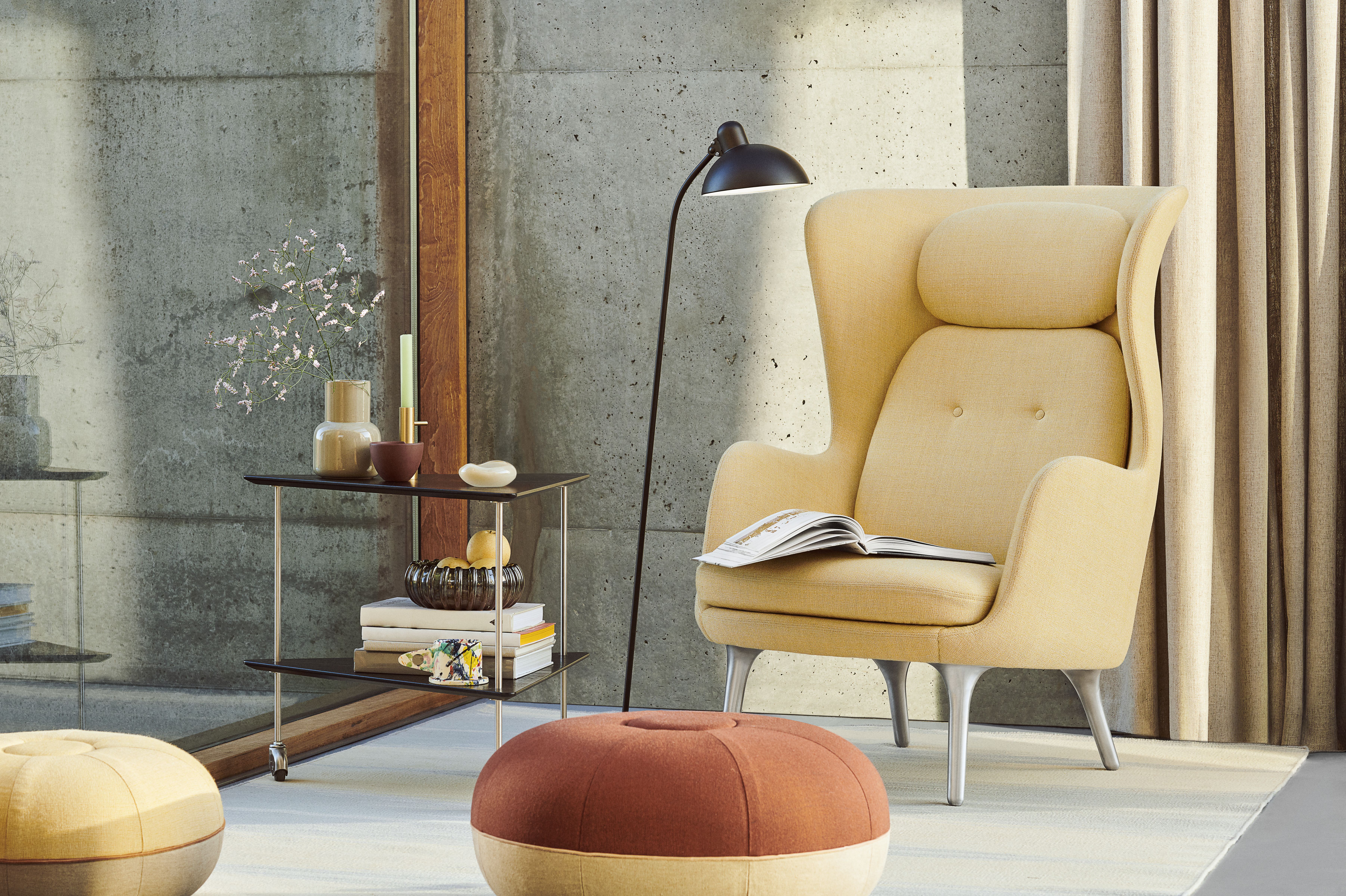 Beige Ro Sessel von Fritz Hansen mit Holzdetails und Buch im modernen Wohnzimmer.