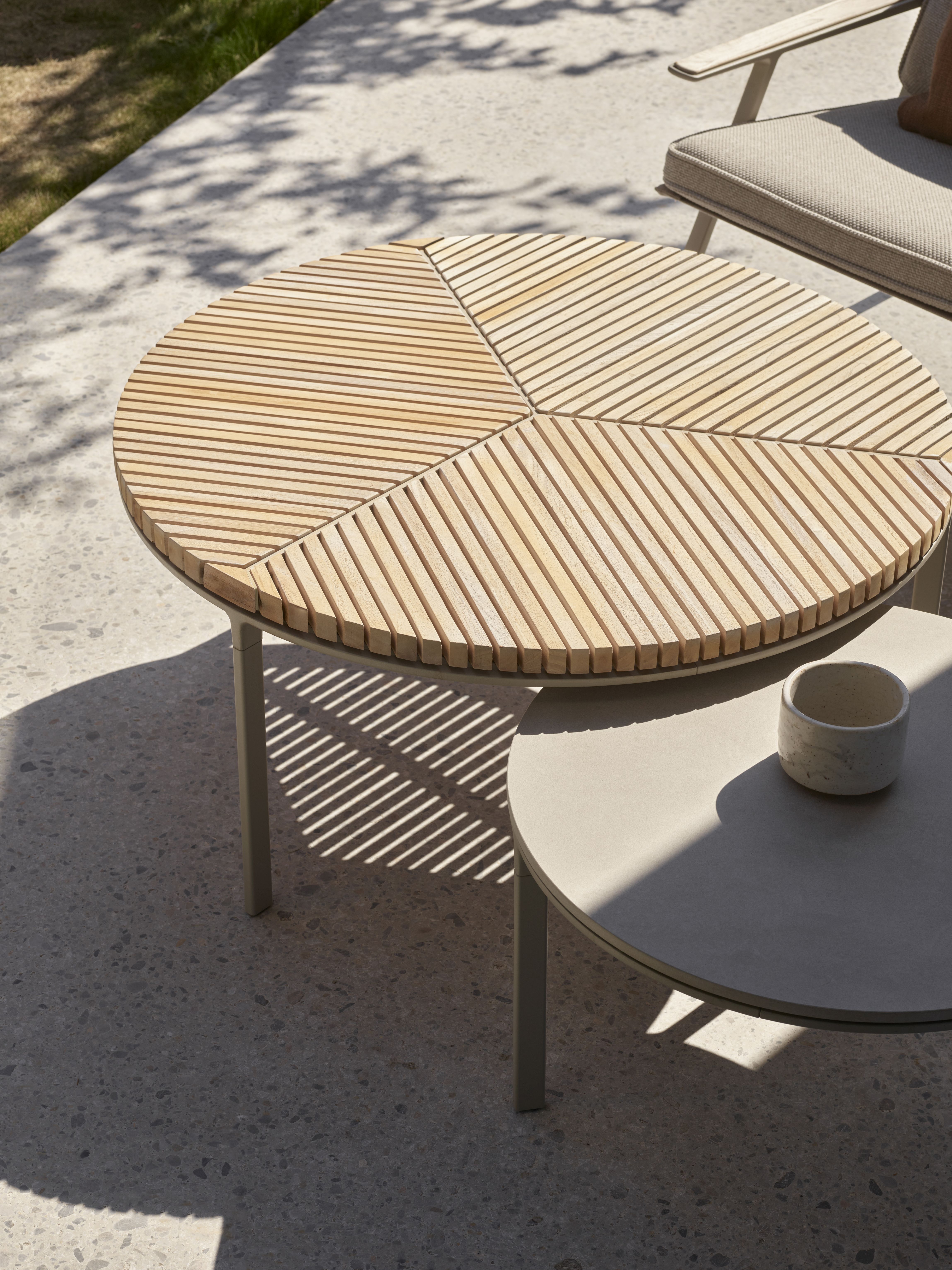 Vipp Outdoor Kaffeetisch mit Holzlamellen-Tischplatte und grauem Metallgestell im Garten.