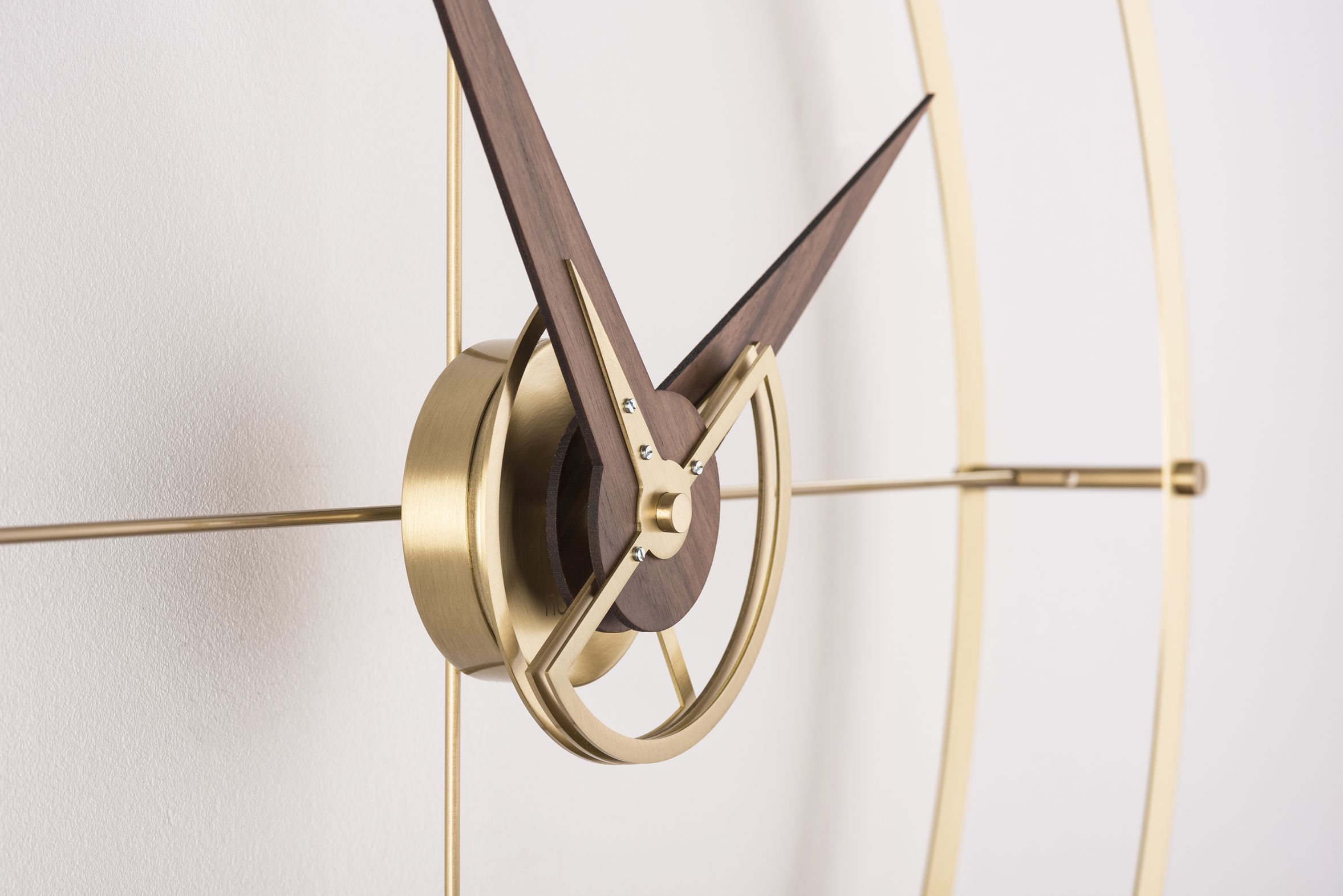 Detailaufnahme der Nomon Doble O Gold Wanduhr mit Holzzeigern und goldenem Rahmen.