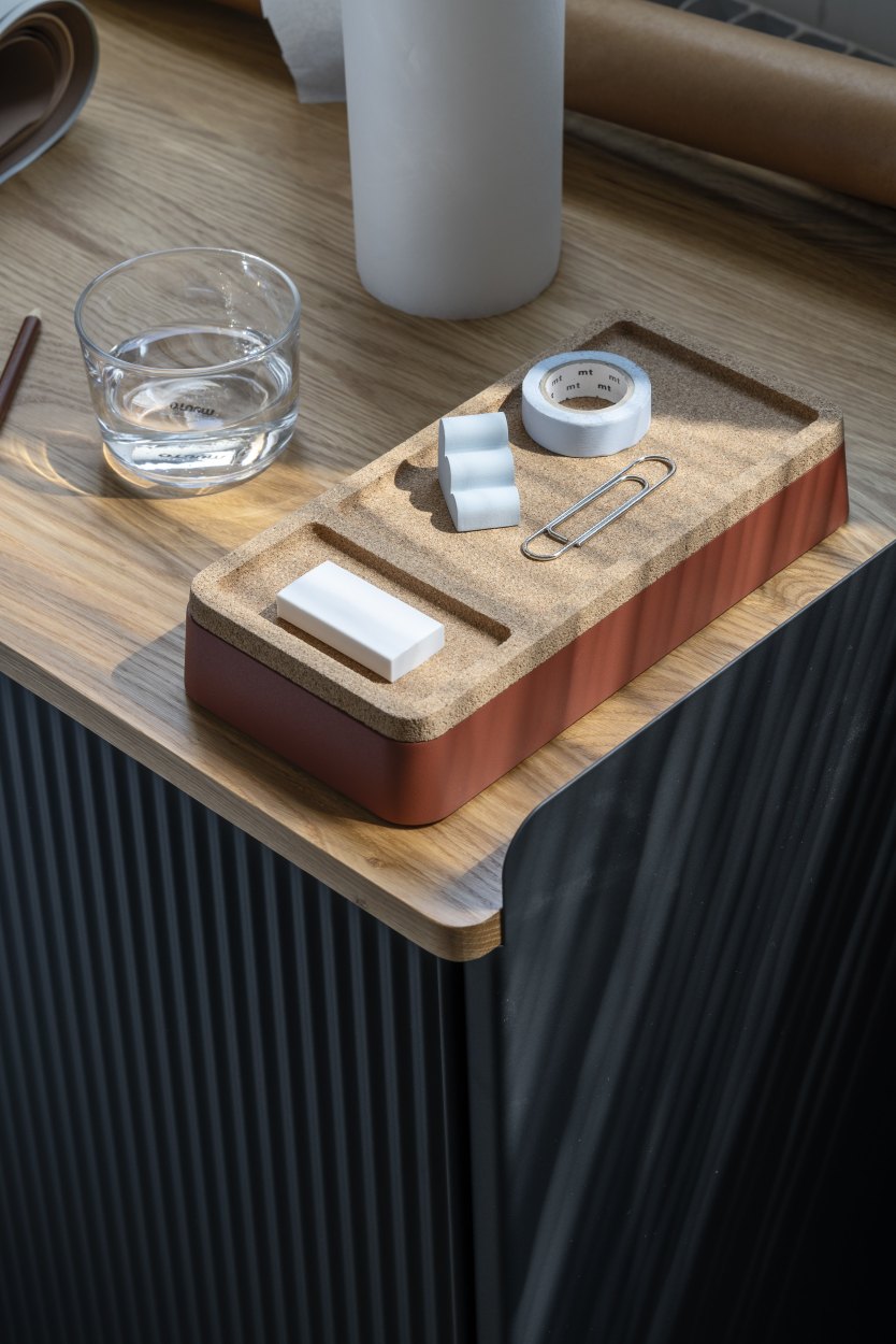 Muuto Arrange Desktop Serie Konfiguration 1: Schreibtisch-Organizer aus Kork mit Büroartikeln auf einem Holzschreibtisch.