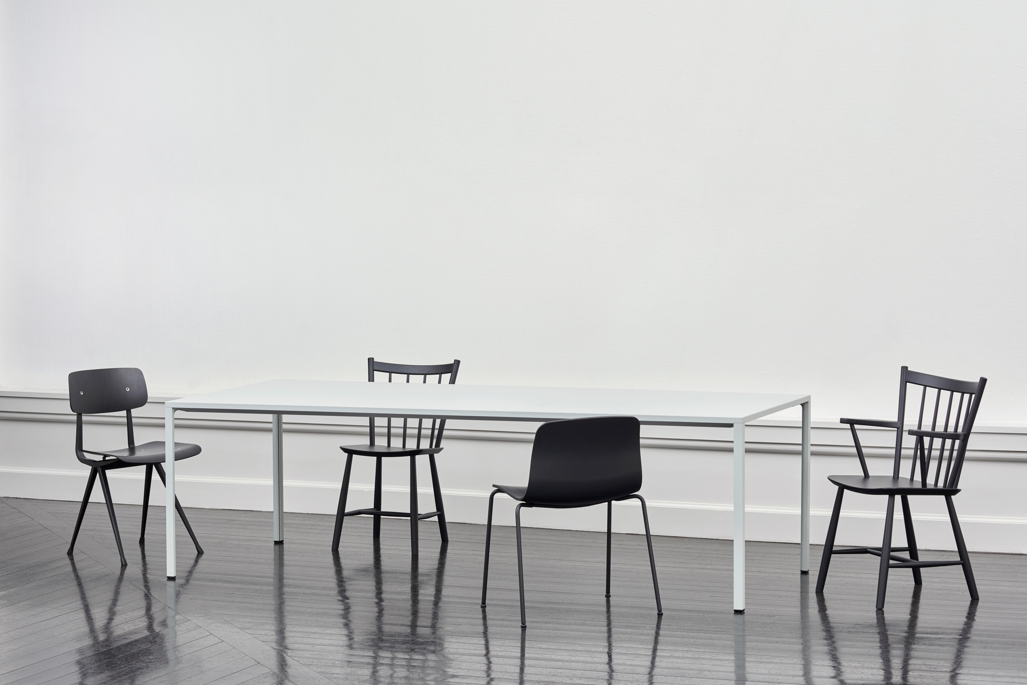 Esstisch mit vier verschiedenen schwarzen Stühlen, darunter ein About a Chair AAC16 Stuhl von Hay.