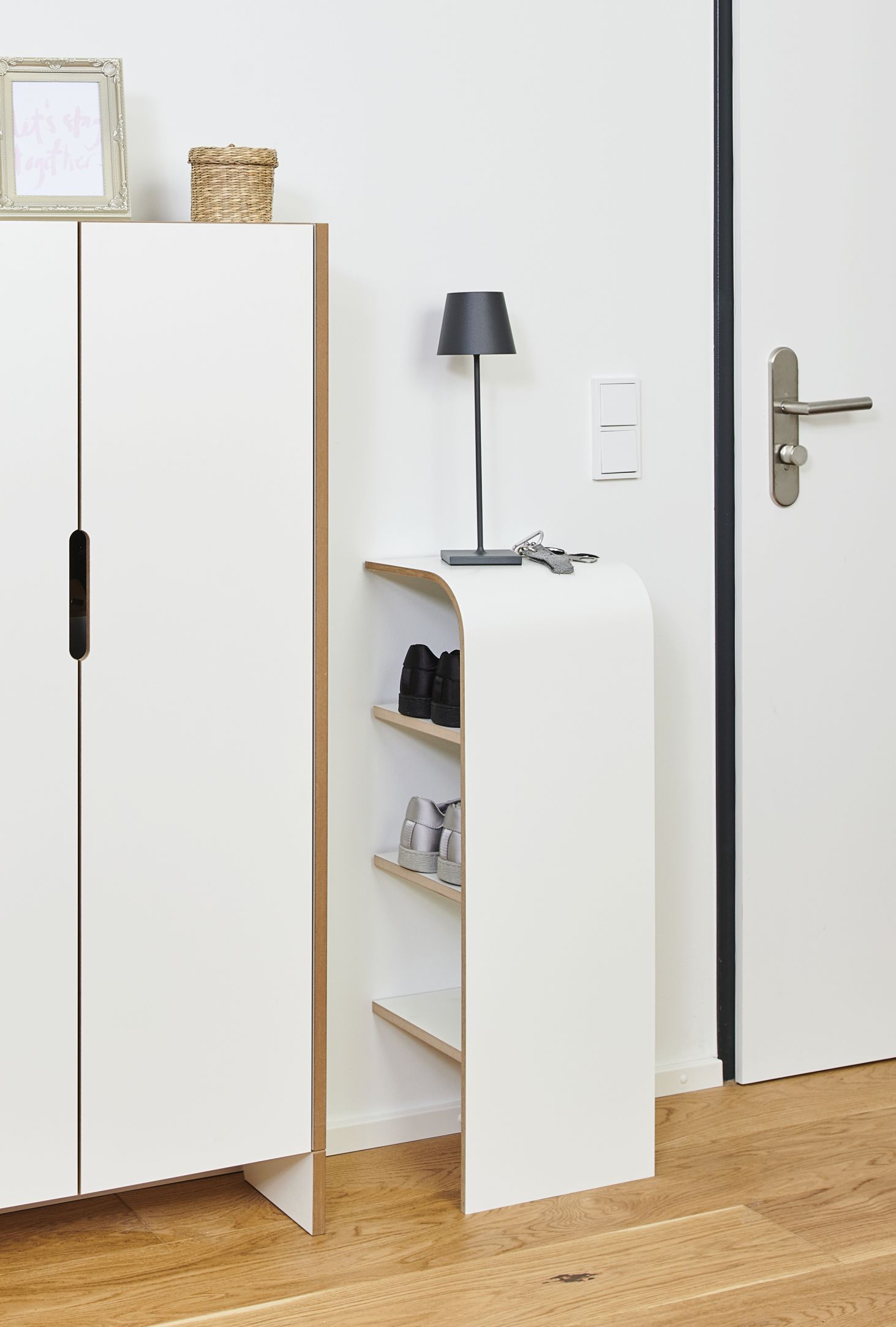 Weißer Schuhschrank mit Ablagen und Lampe im Flur, moderne Schuhaufbewahrung für den Eingangsbereich.