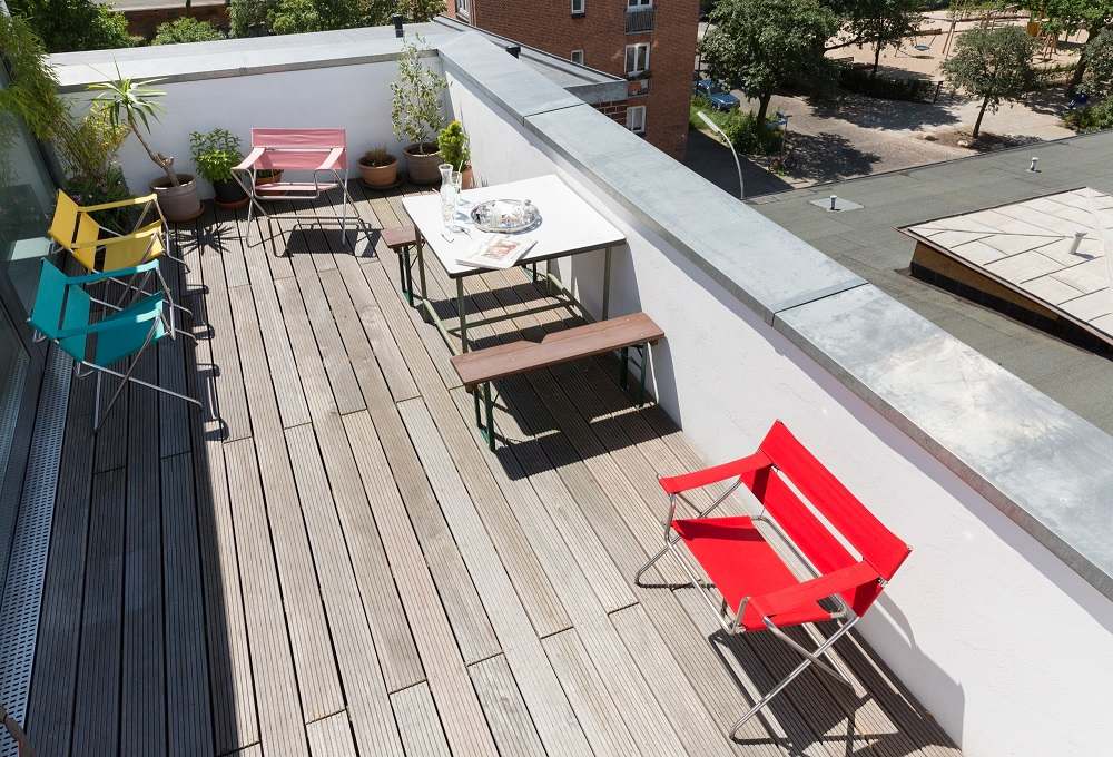 Draufsicht: Mehrere farbige Bauhaus Faltsessel von Tecta auf einer Dachterrasse mit Holzboden.