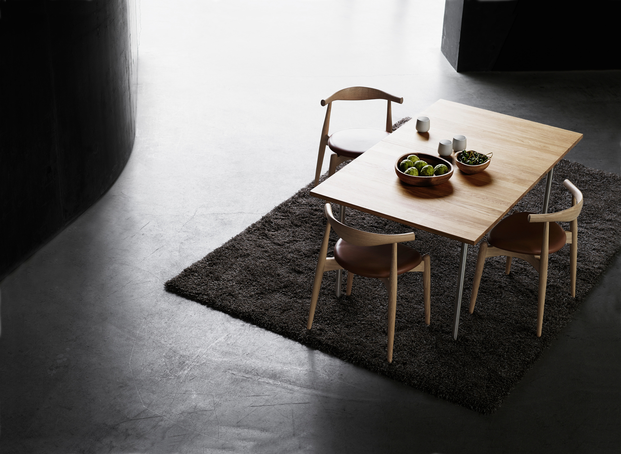 CH20 Elbow Stühle von Carl Hansen & Søn um einen Esstisch auf einem Teppich.