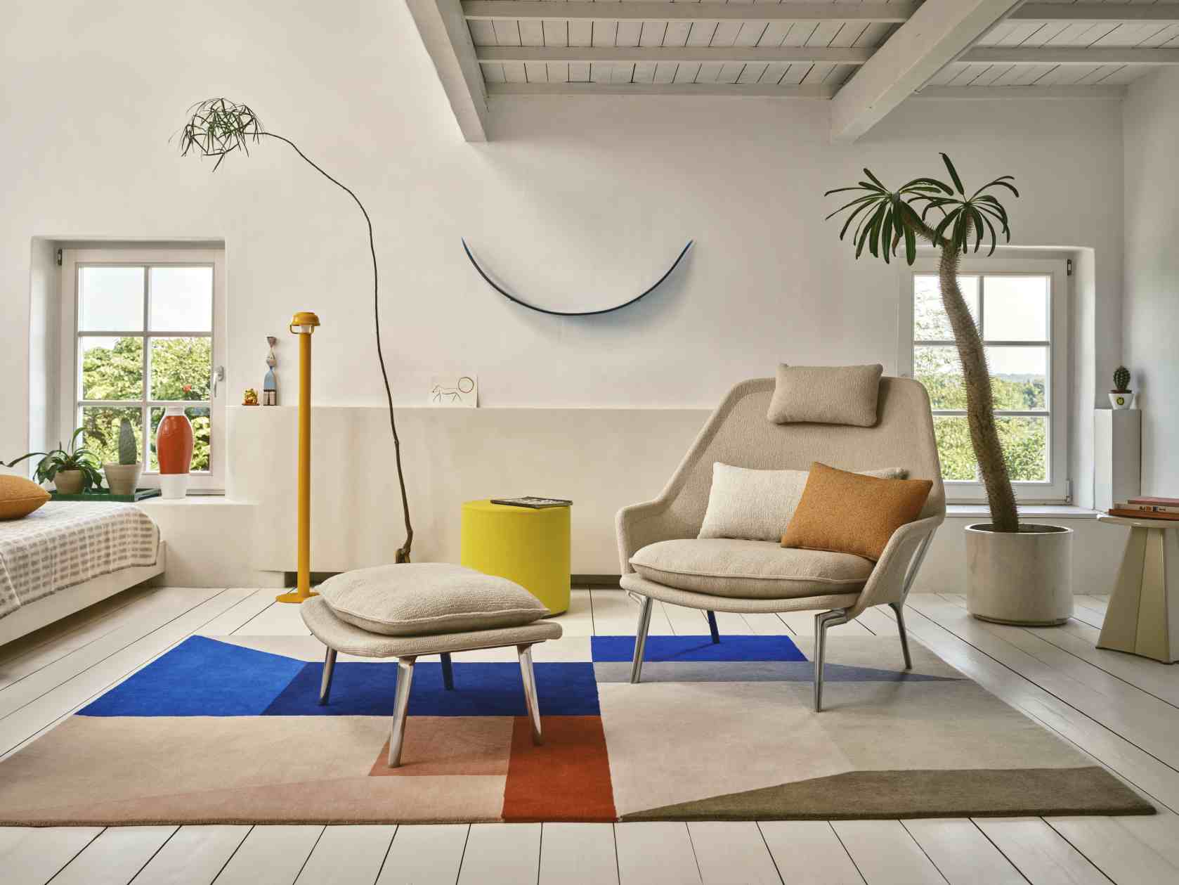Vitra Slow Chair Sessel mit Hocker in hellem Stoffbezug und modernem Wohnzimmerambiente.
