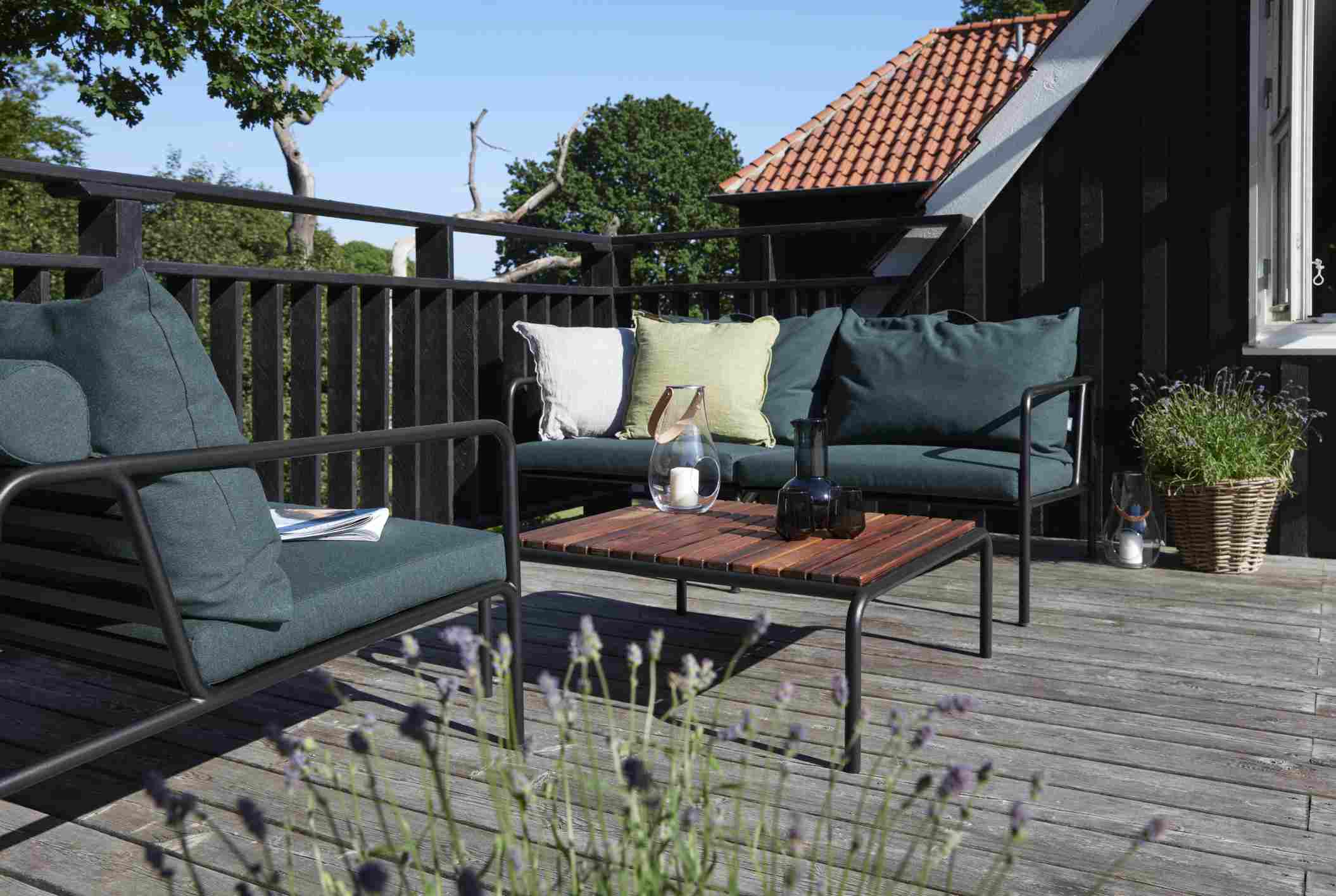Avon 2-Sitzer Sofa von Houe auf Holzterrasse mit Kissen und Tisch, Outdoor-Möbel.