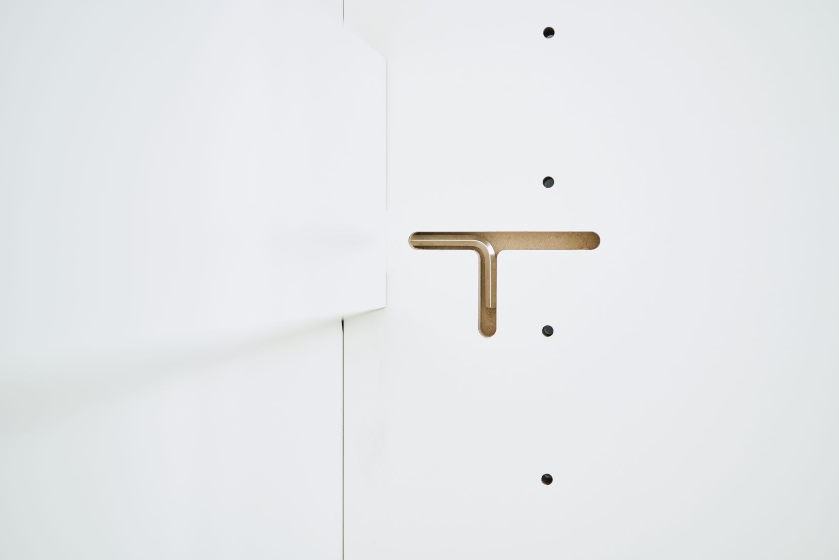 Detailaufnahme des Tojo Schrank Anbaumoduls, weiße Oberfläche mit T-förmiger Aussparung und Verbindungspunkten.