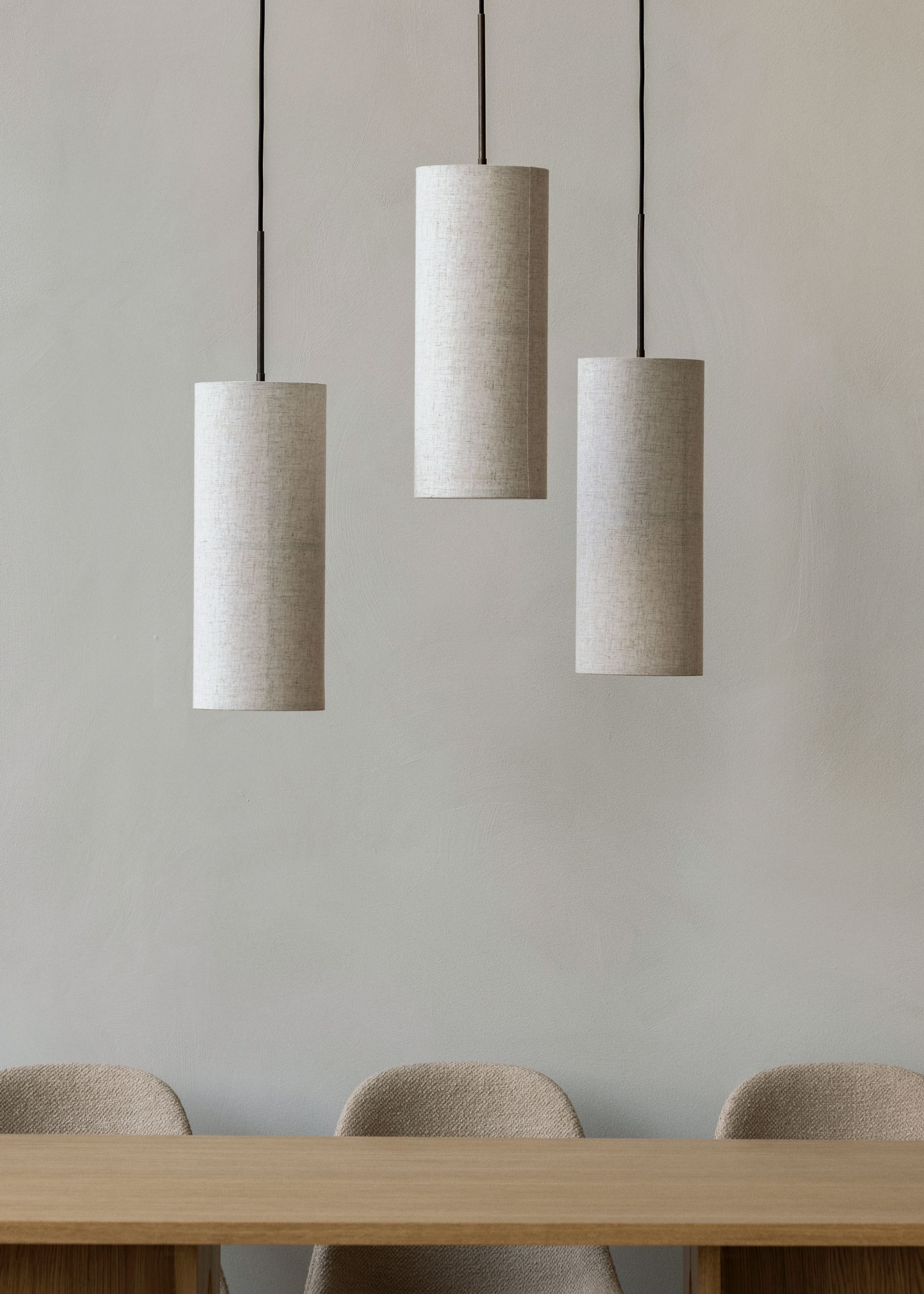 Drei weiße Hashira Pendelleuchten von Audo über einem Holztisch, moderne Innenraumbeleuchtung.