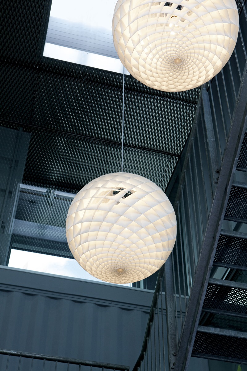 Zwei Louis Poulsen Patera Pendelleuchten in einem modernen Treppenhaus, sphärische Designerlampe mit geometrischem Muster.