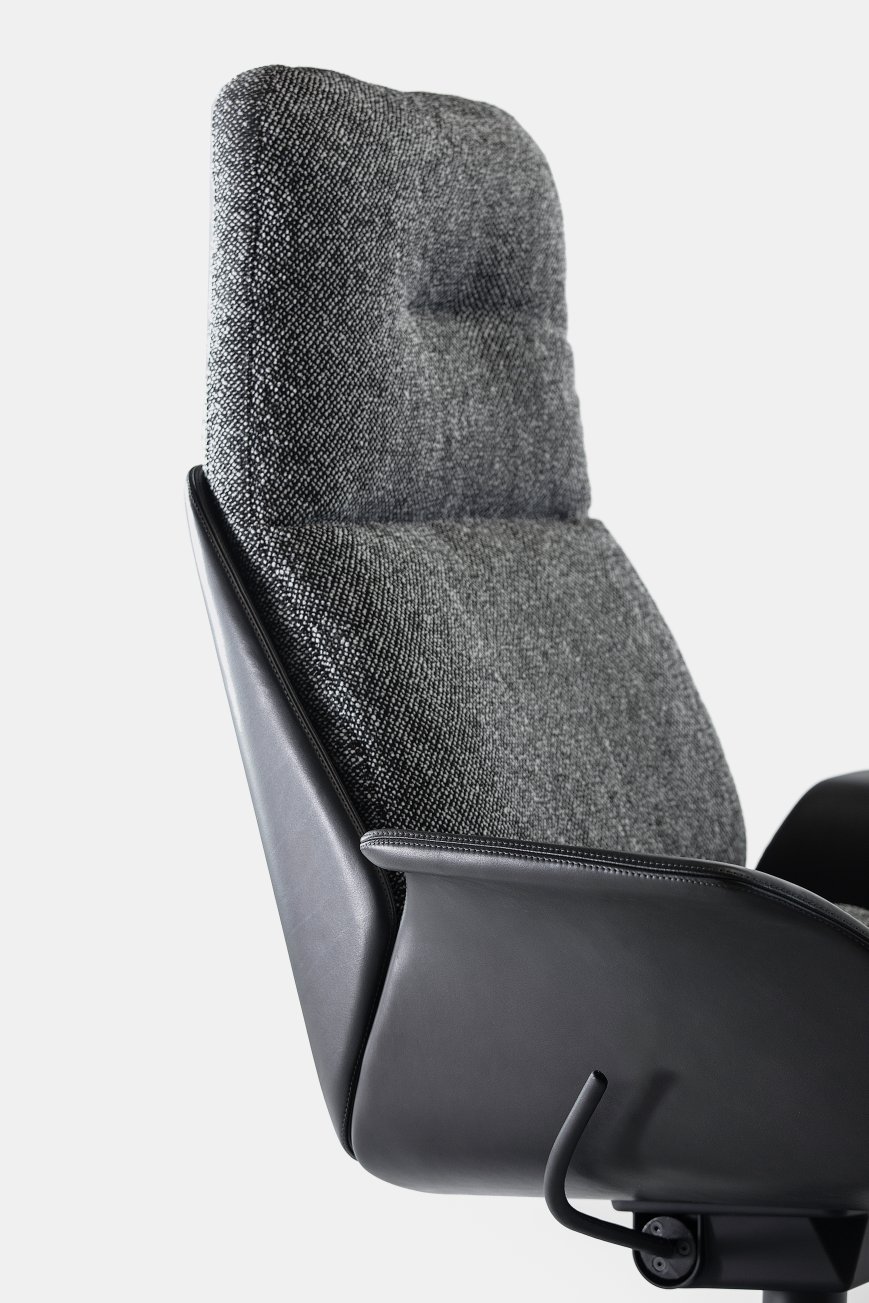 Detailaufnahme vom Prostoria Rei Sessel: Grauer Stoffbezug, schwarze Lederarmlehnen, modernes Design für Wohnzimmer und Büro.