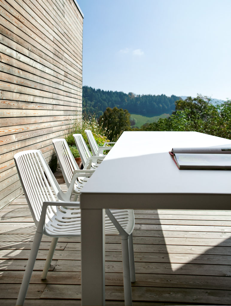 Rion Outdoor Sessel: Weißes 2er-Set Gartenstühle aus Metall auf Holzterrasse mit Tisch und Aussicht.