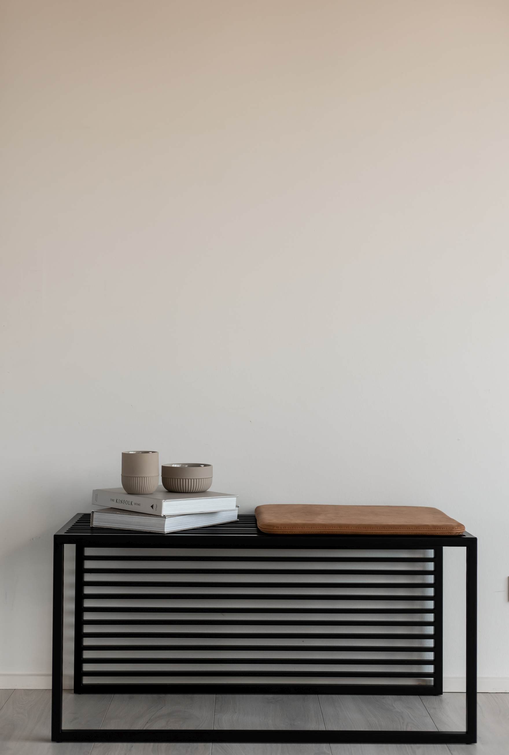 Element Bench Bank von Novoform mit schwarzem Metallgestell, Lederkissen, Büchern und Deko-Schalen.
