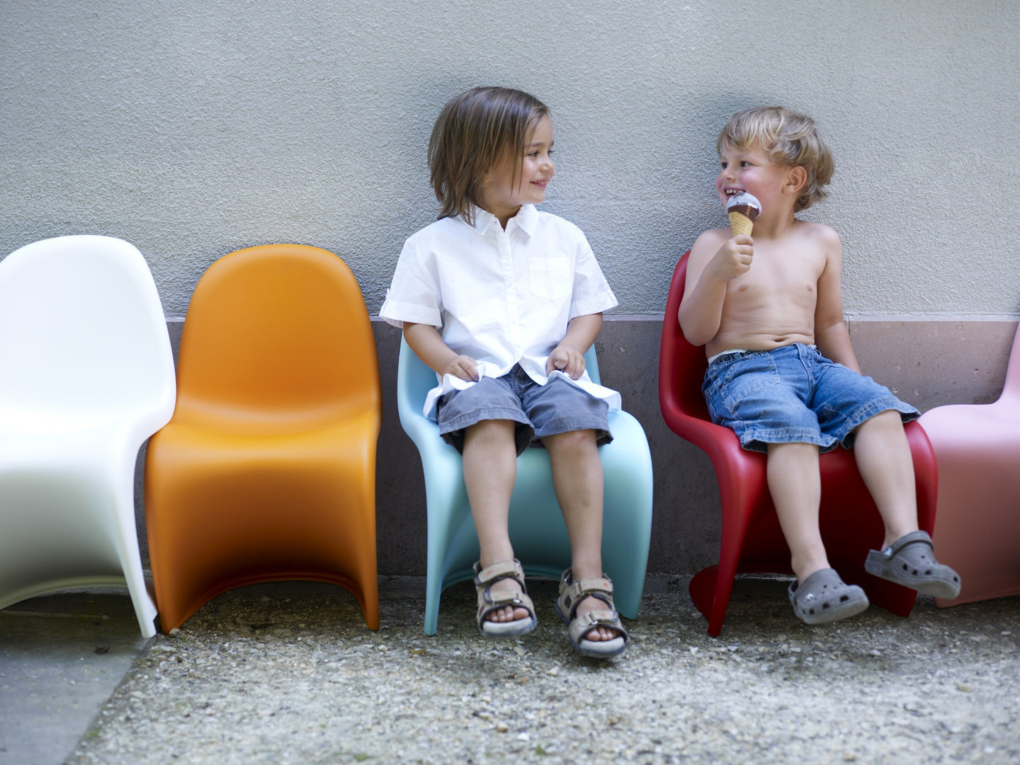 Zwei Kinder sitzen auf farbigen Panton Junior Stühlen, einer davon in Soft Mint.