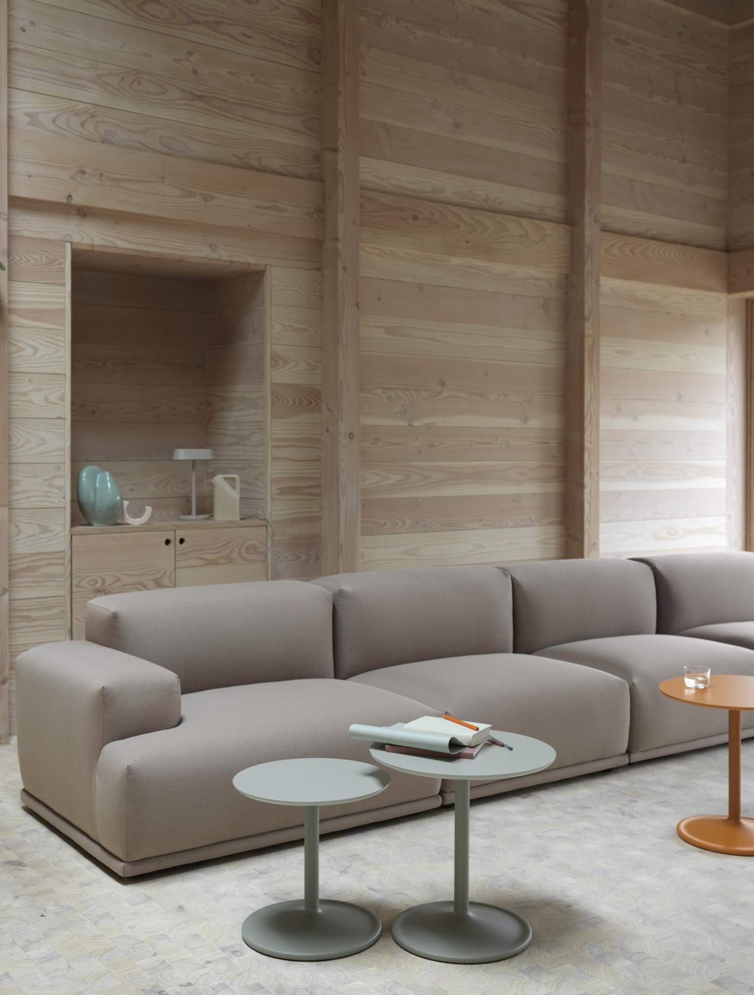Muuto Connect Soft Modular Sofa in Clay Farbe, modernes Ecksofa mit Beistelltischen vor Holzwand.