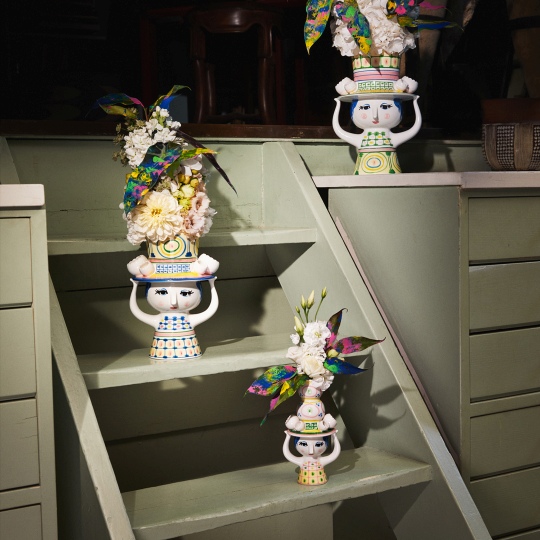 Drei Bjorn Wiinblad Lady with Hat Vasen auf einer grünen Treppe, gefüllt mit Blumen.