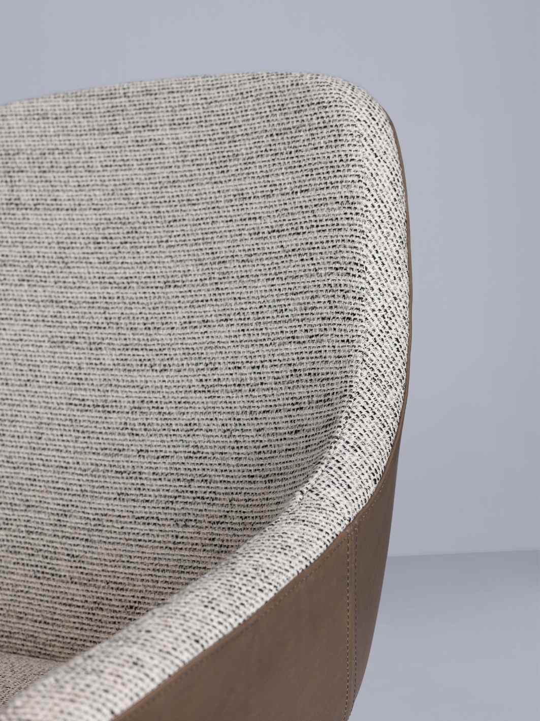 Detailaufnahme des Morph Dining Chair Stuhls mit grau meliertem Stoffbezug und braunem Lederakzent.