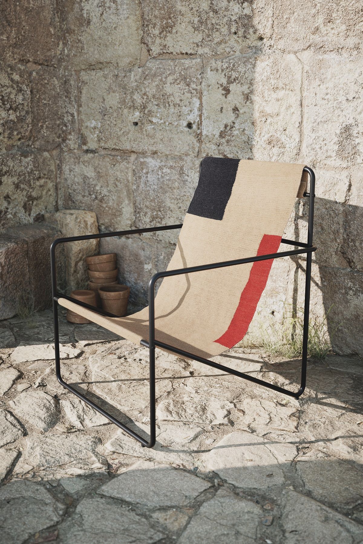 Desert Chair Loungesessel von Ferm Living mit schwarzem Metallgestell und Stoffbezug in Beige, Schwarz und Rot.