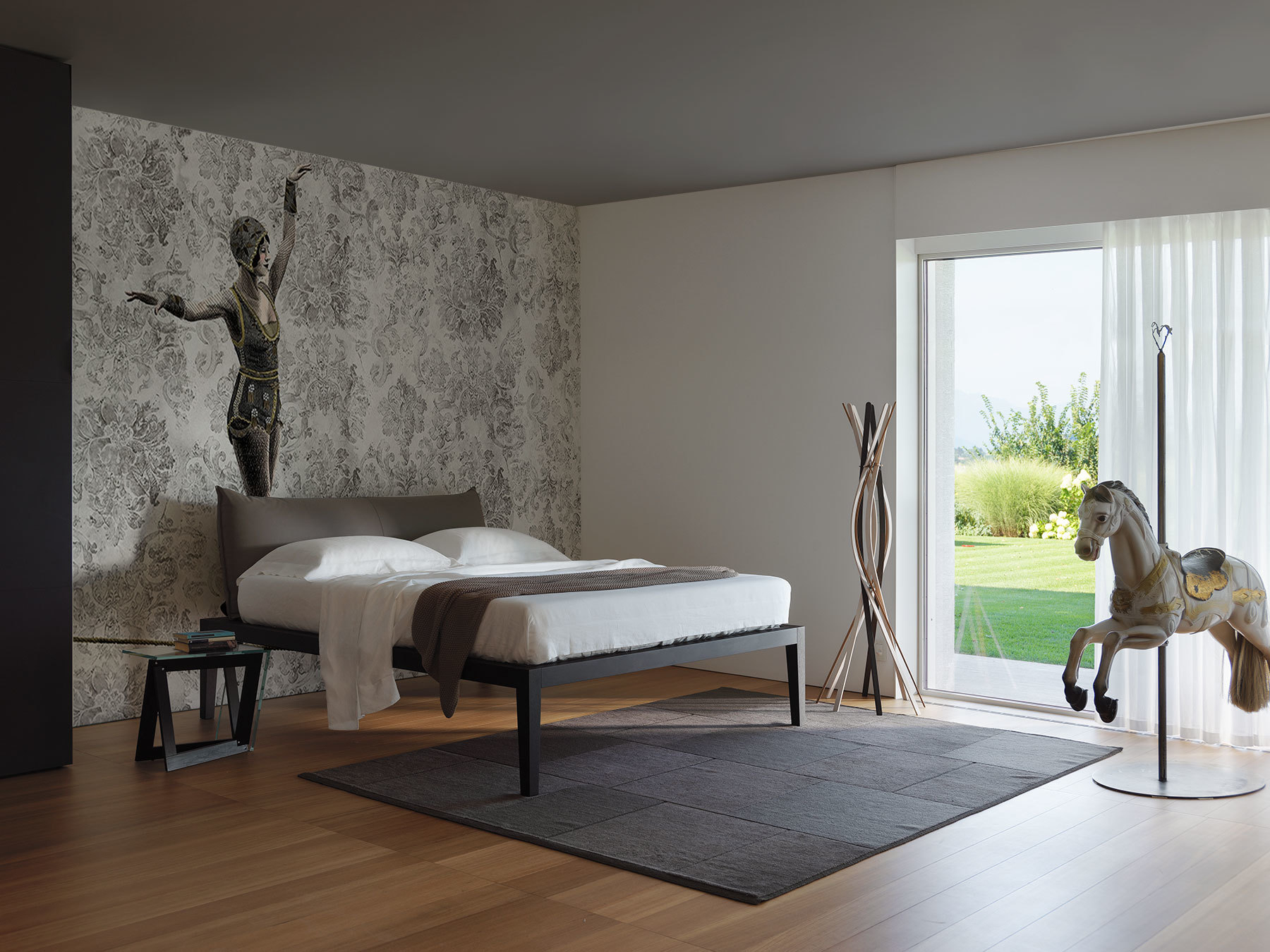 Casamania Horm Twist Garderobenständer aus Holz im modernen Schlafzimmer mit Bett und Dekoration.