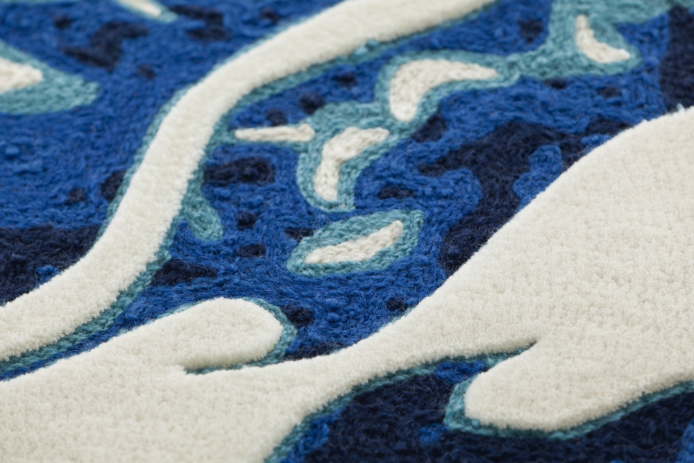 Detailaufnahme des Cadeneta Blue Teppichs von GAN, mit blauem Muster und weißen Akzenten. Handgefertigter Wollteppich.