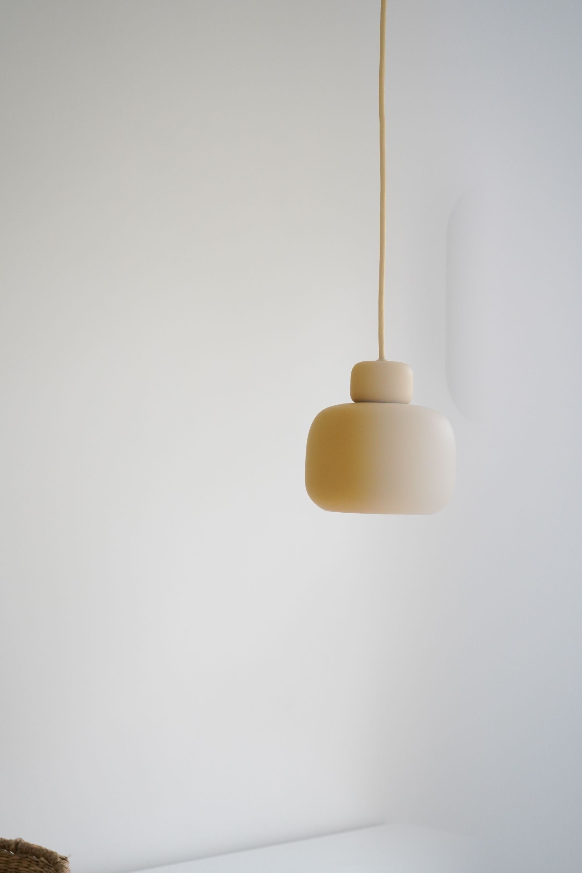 Nahaufnahme der kleinen Woud Stone Pendant Pendelleuchte in Beige vor einer weißen Wand.