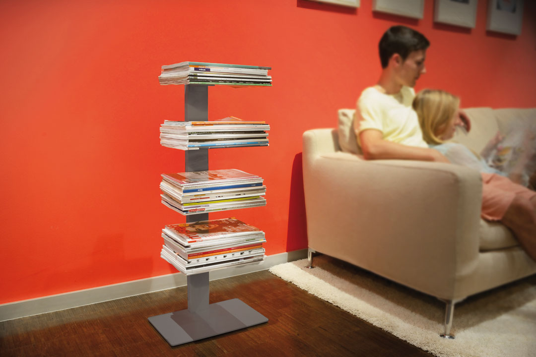 Booksbaum Magazinregal: Modernes Standregal in Weiß, gefüllt mit Zeitschriften, neben einer Couch.