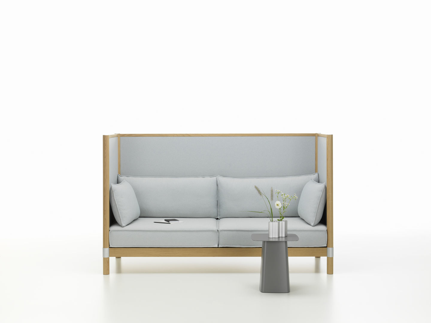 Grauer Vitra Beistelltisch aus Metall neben einem hellblauen Sofa mit Holzelementen.
