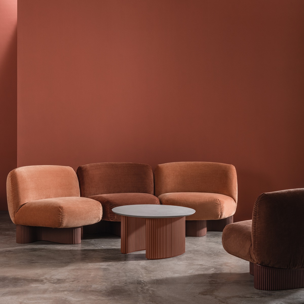 Bolete Couchtisch von Andreu World mit modularen Loungesesseln in Terrakotta vor passender Wand.