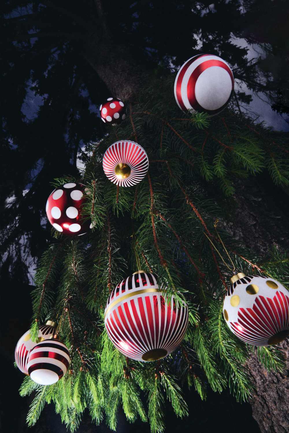 Nahaufnahme von Alessi Weihnachtskugeln (NZ04SET1 Delight) in Rot, Weiß und Gold am Weihnachtsbaum.