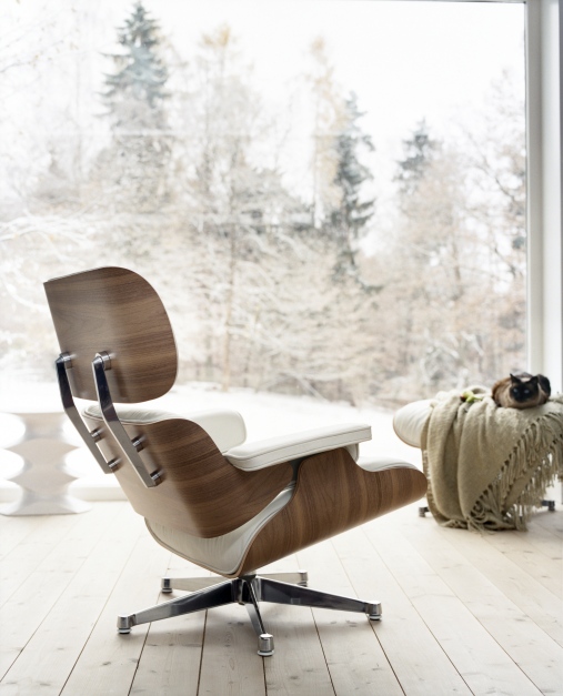 Eames Lounge Chair Sessel mit weißem Leder und Nussbaumholz vor verschneiter Winterlandschaft.