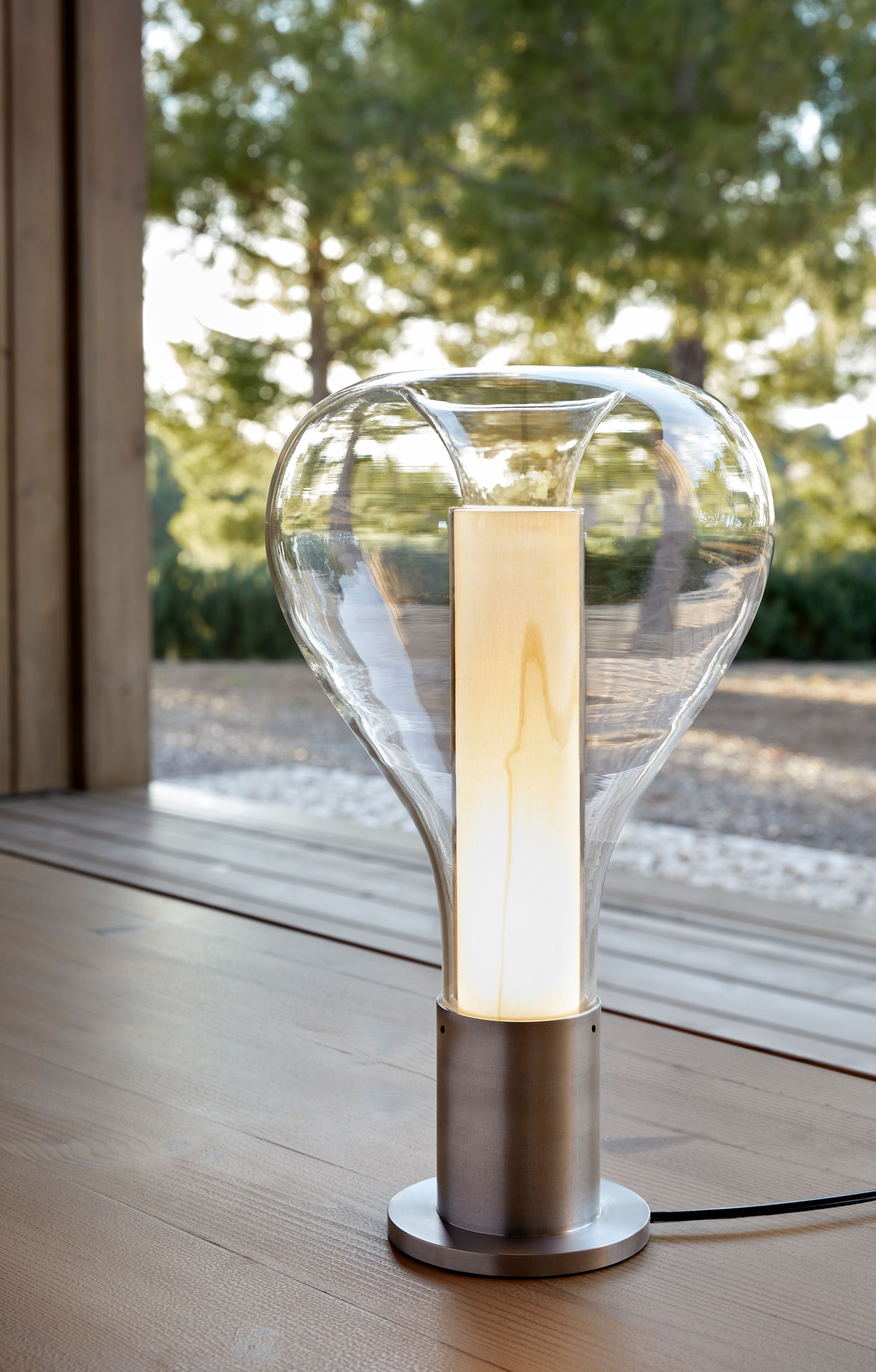 Eris Tischleuchte von LZF Lamps mit Aluminiumsockel und hellrosa Schirm auf Holztisch.