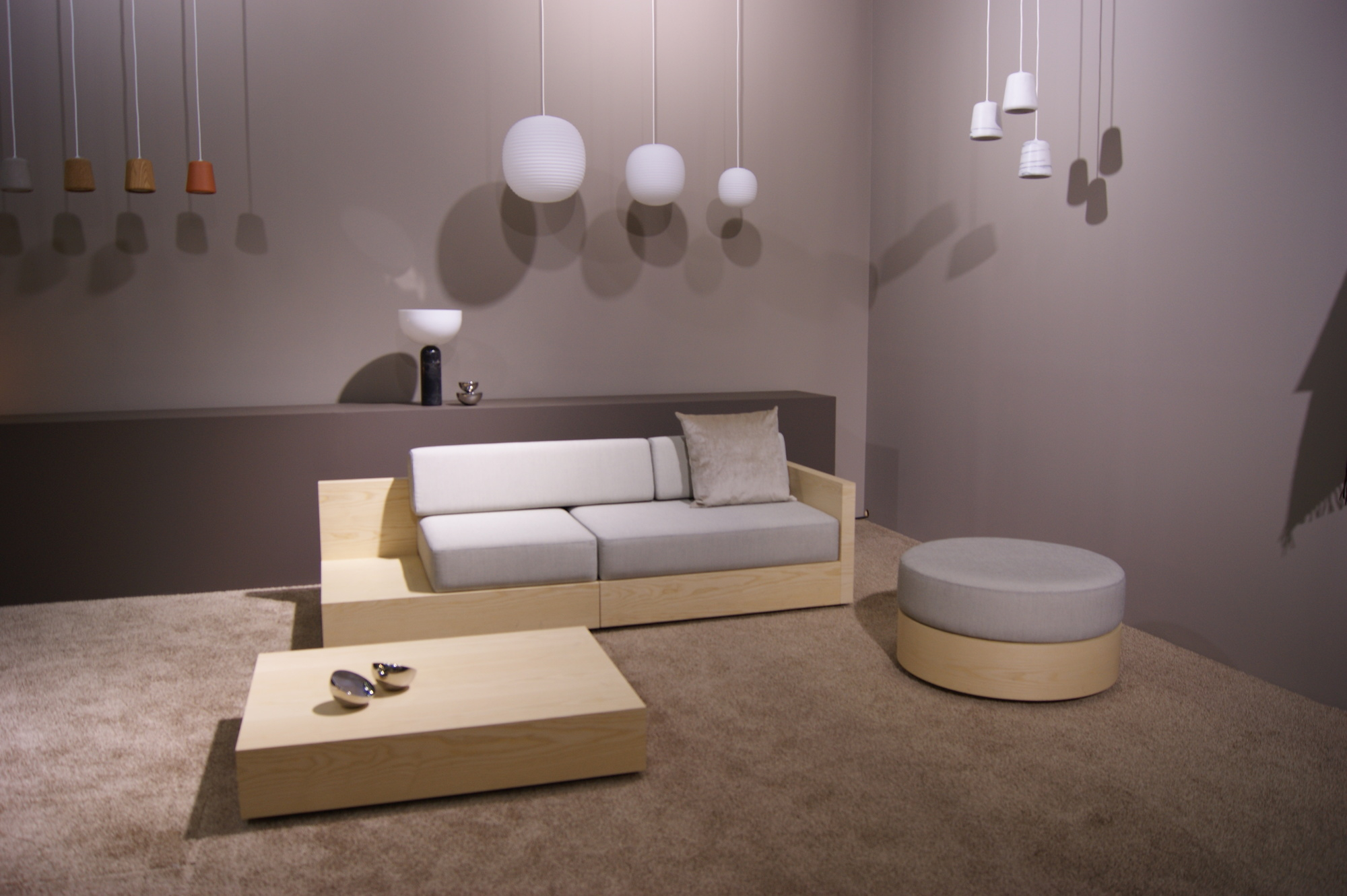 New Works Lantern Pendant Pendelleuchten in verschiedenen Formen und Farben über modernem Wohnzimmer mit Sofa.
