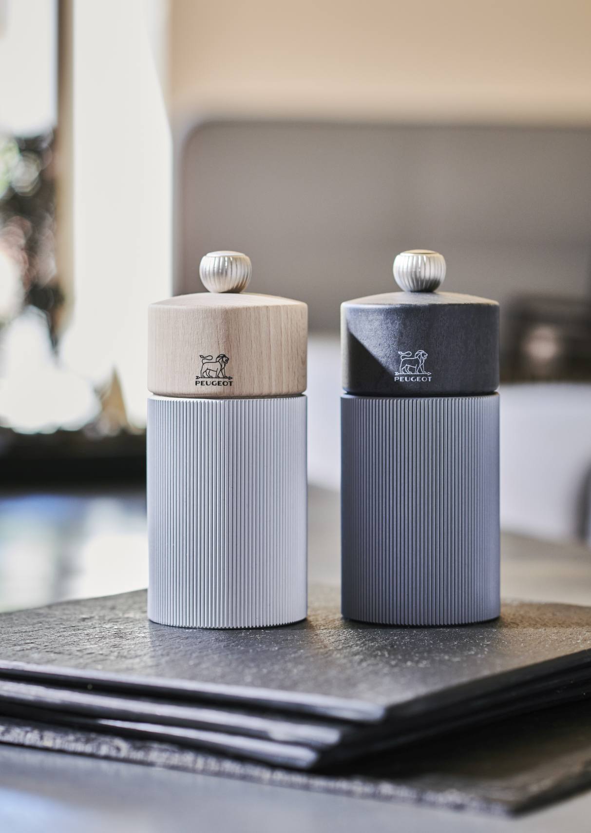 Zwei Peugeot Line Pfeffermühlen in Graphit und Carbon, moderne Küchenaccessoires für stilvolles Würzen.