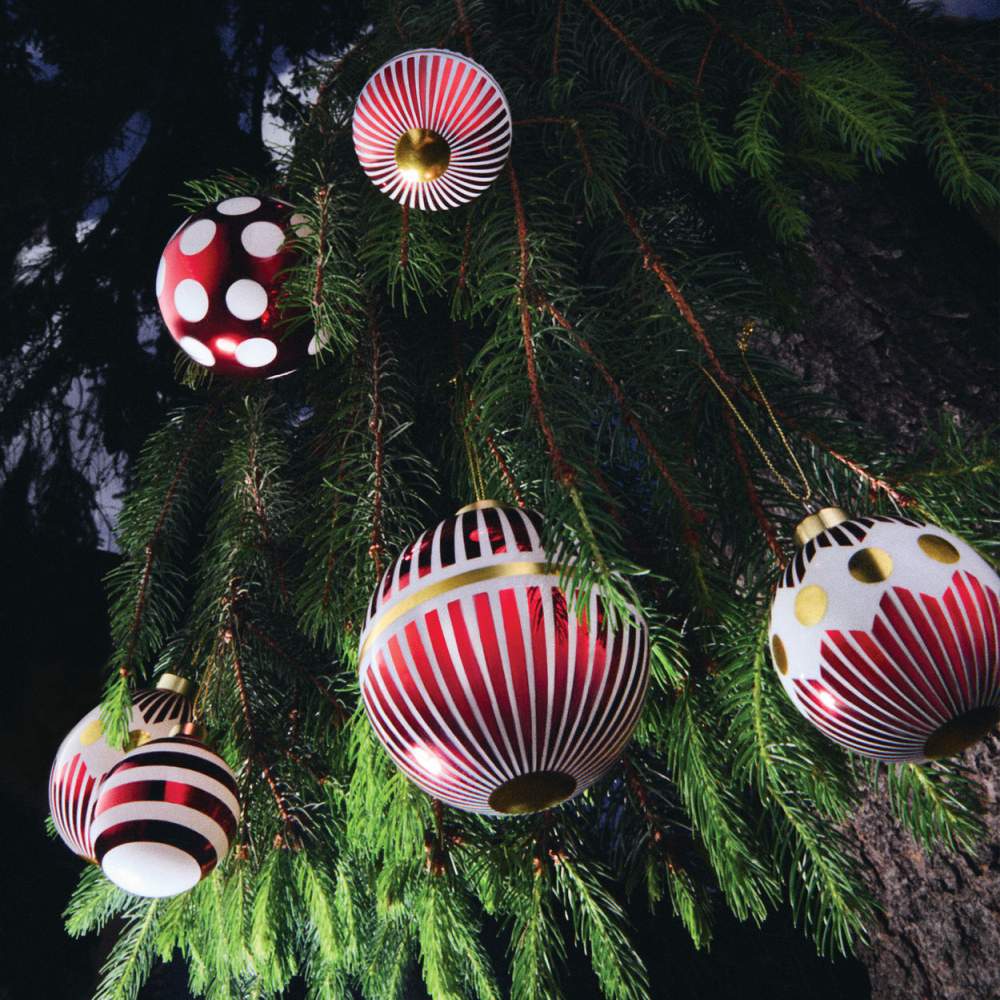 Alessi Weihnachtskugeln NZ04 1 Delight, rot-weiß gemustert, hängen an einem geschmückten Weihnachtsbaum.