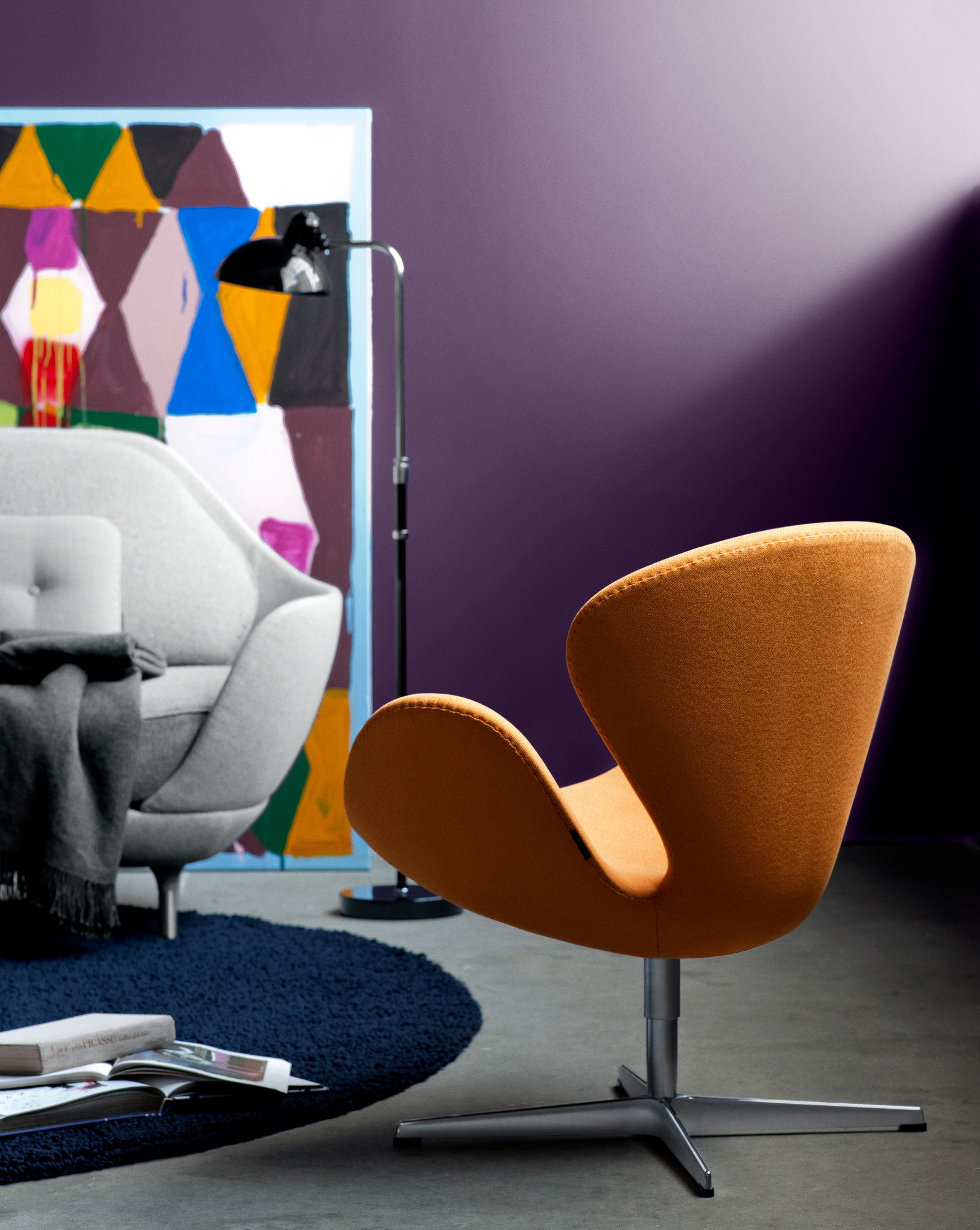 Nahaufnahme einer orangefarbenen Fritz Hansen Swan Chair mit KAISER idell 6580 F Stehleuchte im Hintergrund.