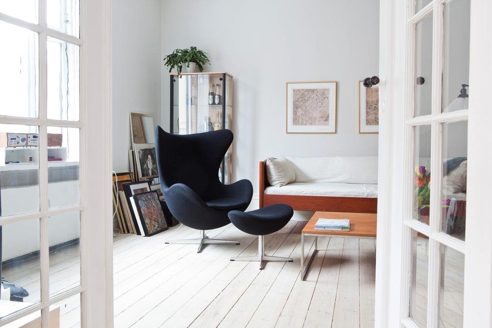 Schwarzer Egg Chair Sessel mit Hocker von Fritz Hansen in stilvollem Wohnzimmer auf weißem Holzboden.