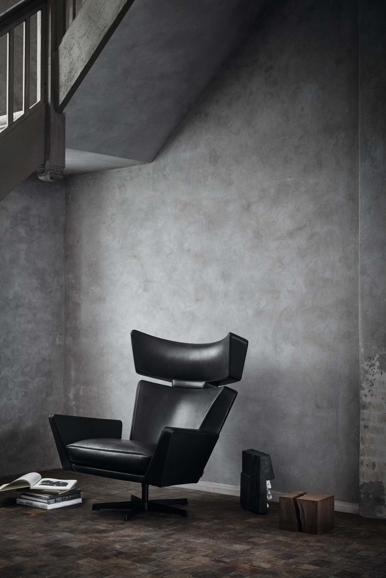 Schwarzer Oksen Sessel von Fritz Hansen im Interieur mit Betonwand und Holzfußboden.
