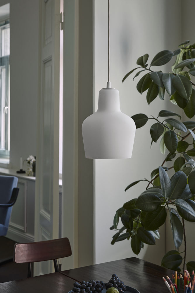 Weiße Artek A440 Hängeleuchte über Esstisch mit Obst und Zimmerpflanze im modernen Interieur.