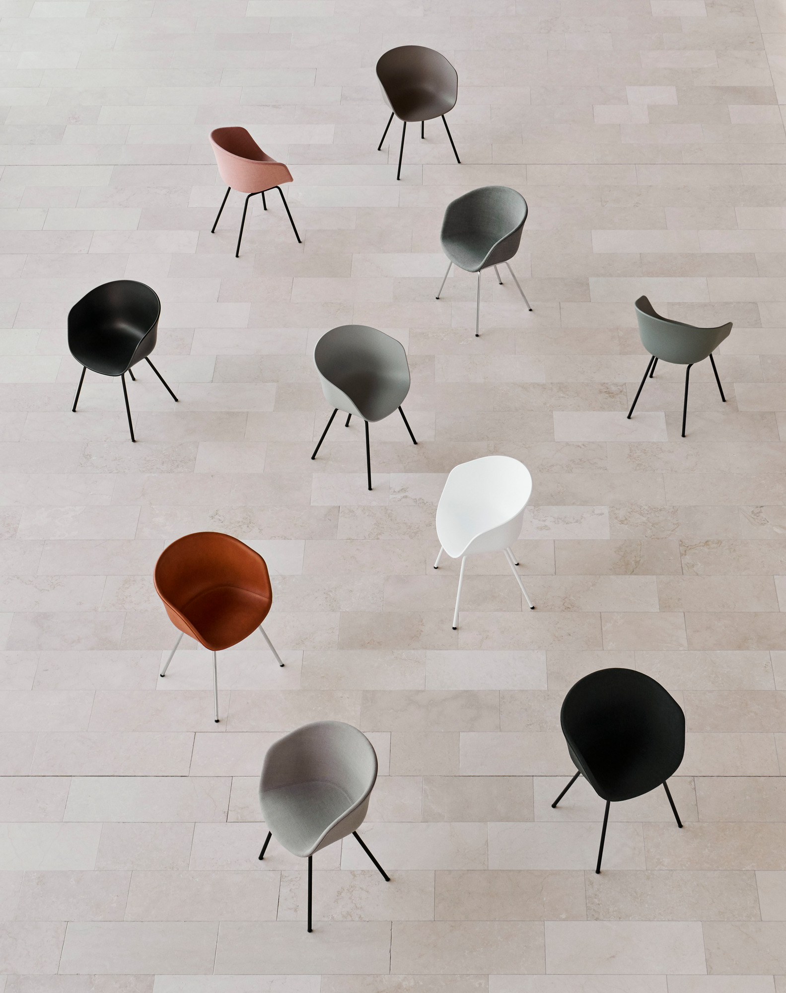 Draufsicht von mehreren Hay About A Chair AAC26 Stühlen in verschiedenen Farben auf einem hellen Fliesenboden.