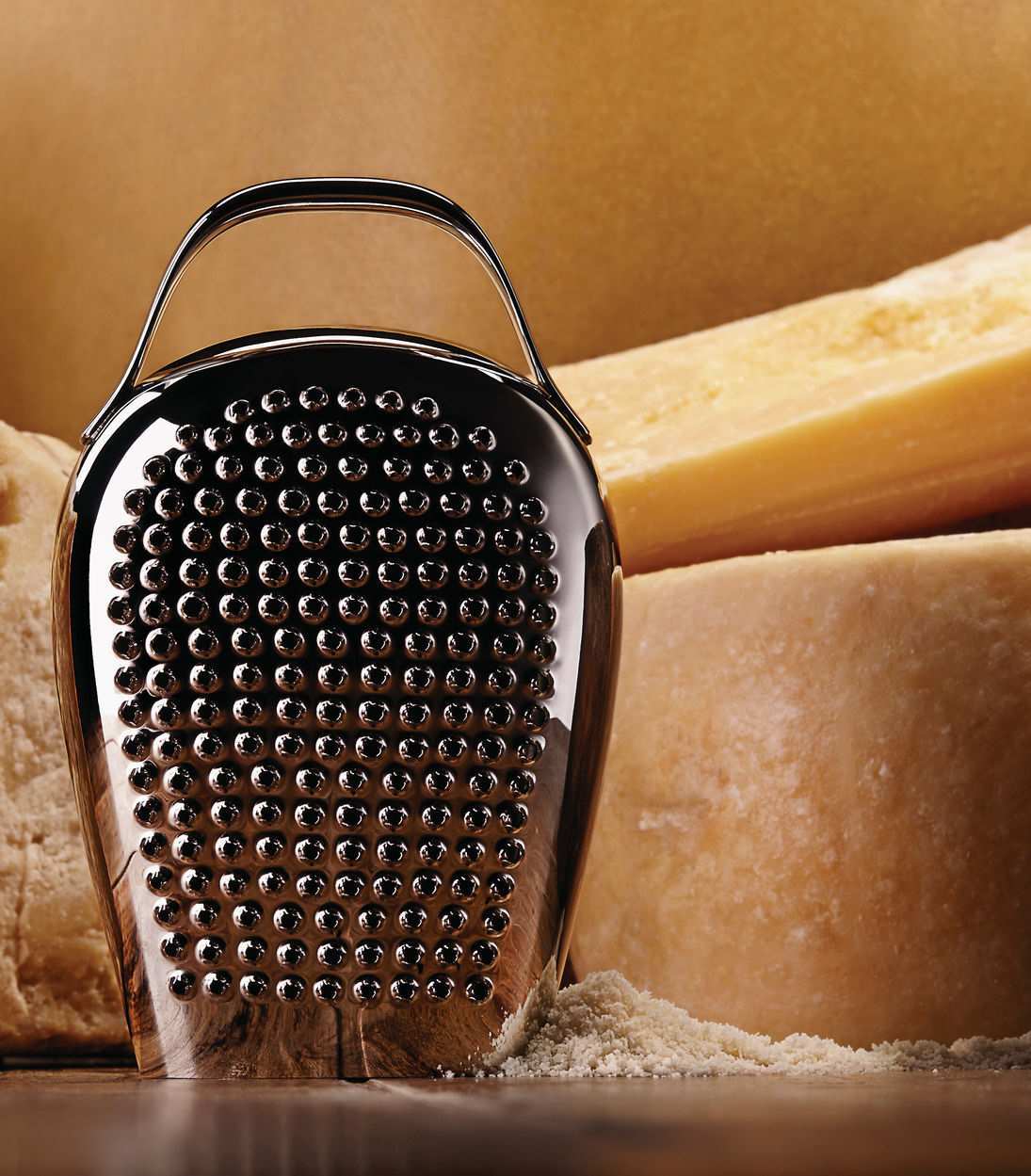 Alessi Käsereibe "Cheese Please" CHB02 aus Edelstahl, mit Käse im Hintergrund.
