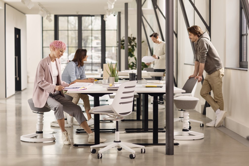 Numo Task Bürostuhl von Aeris im modernen Büro mit Mitarbeitern, ergonomischer Drehstuhl mit Säule und Rollen.