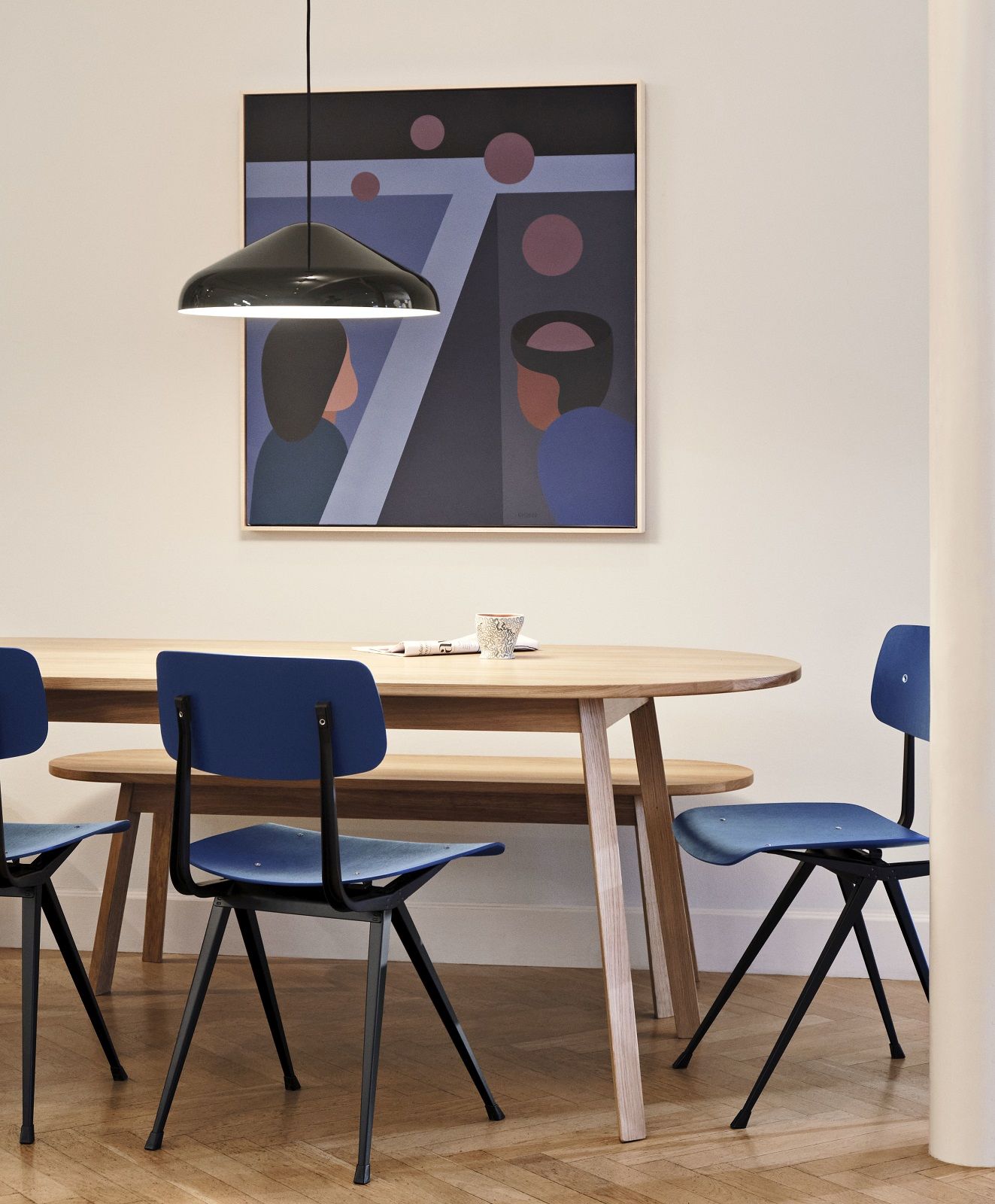 Hay Triangle Leg Table Esstisch mit blauen Stühlen und Bank in modernem Esszimmer.