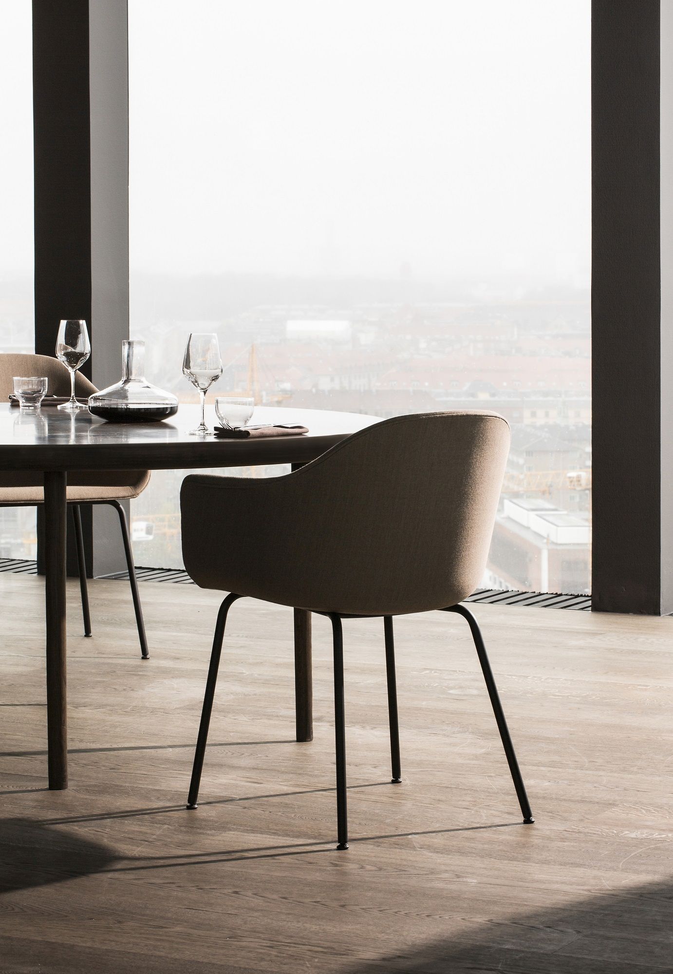 Audo Copenhagen Harbour Dining Chair Stuhl in Beige am Esstisch mit Blick auf die Stadt.