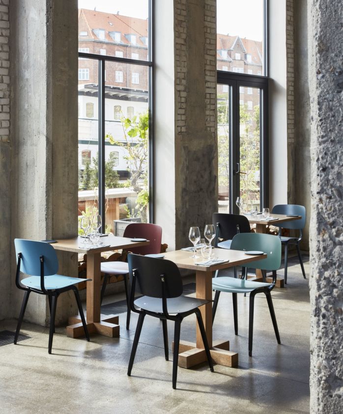 Innenansicht eines Restaurants mit mehreren Hay Revolt Stühlen in verschiedenen Farben an Holztischen.