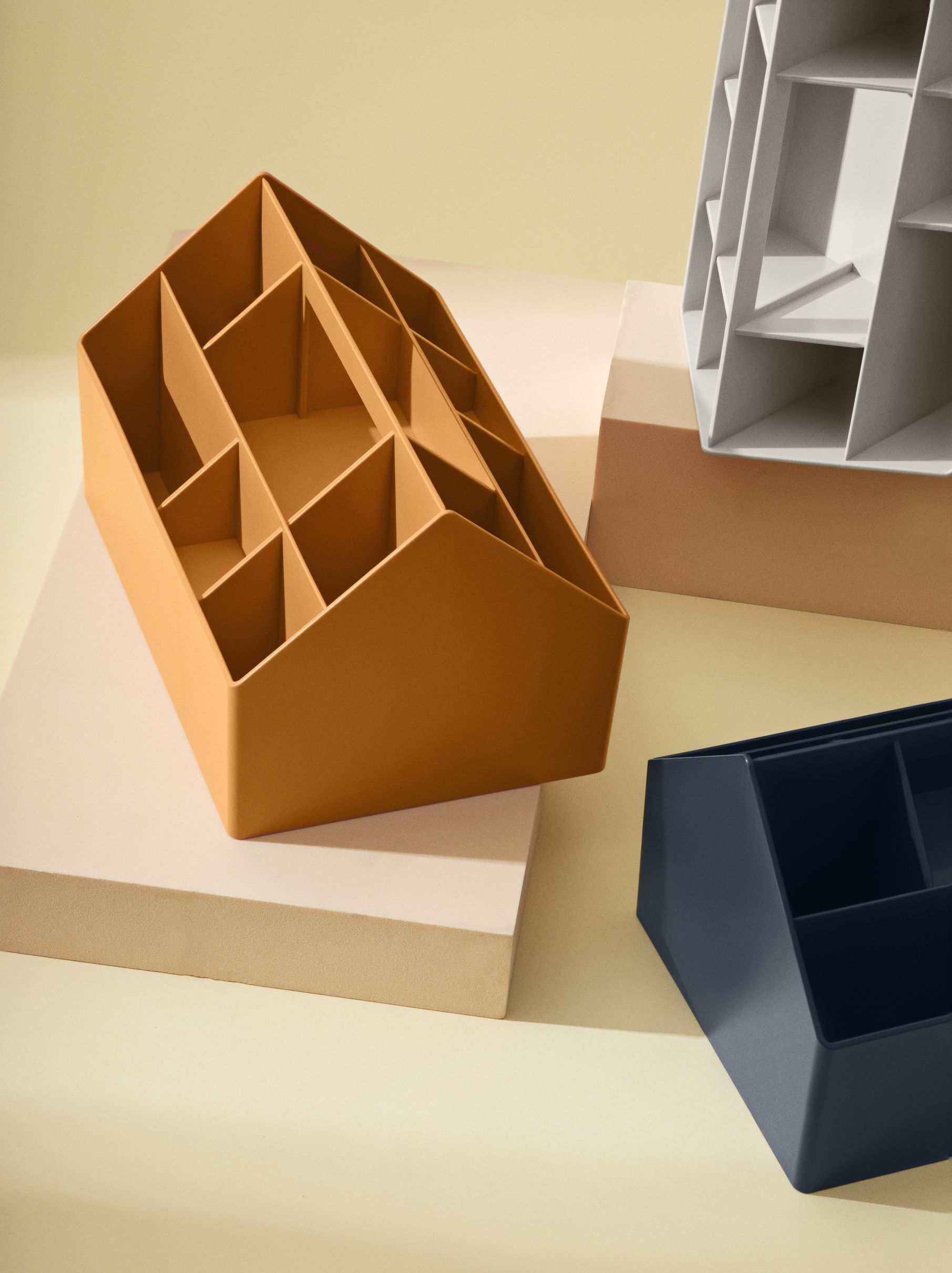 Muuto Sketch Toolbox Organisationsbox in Mitternachtsblau, orange und weiß auf Podesten.