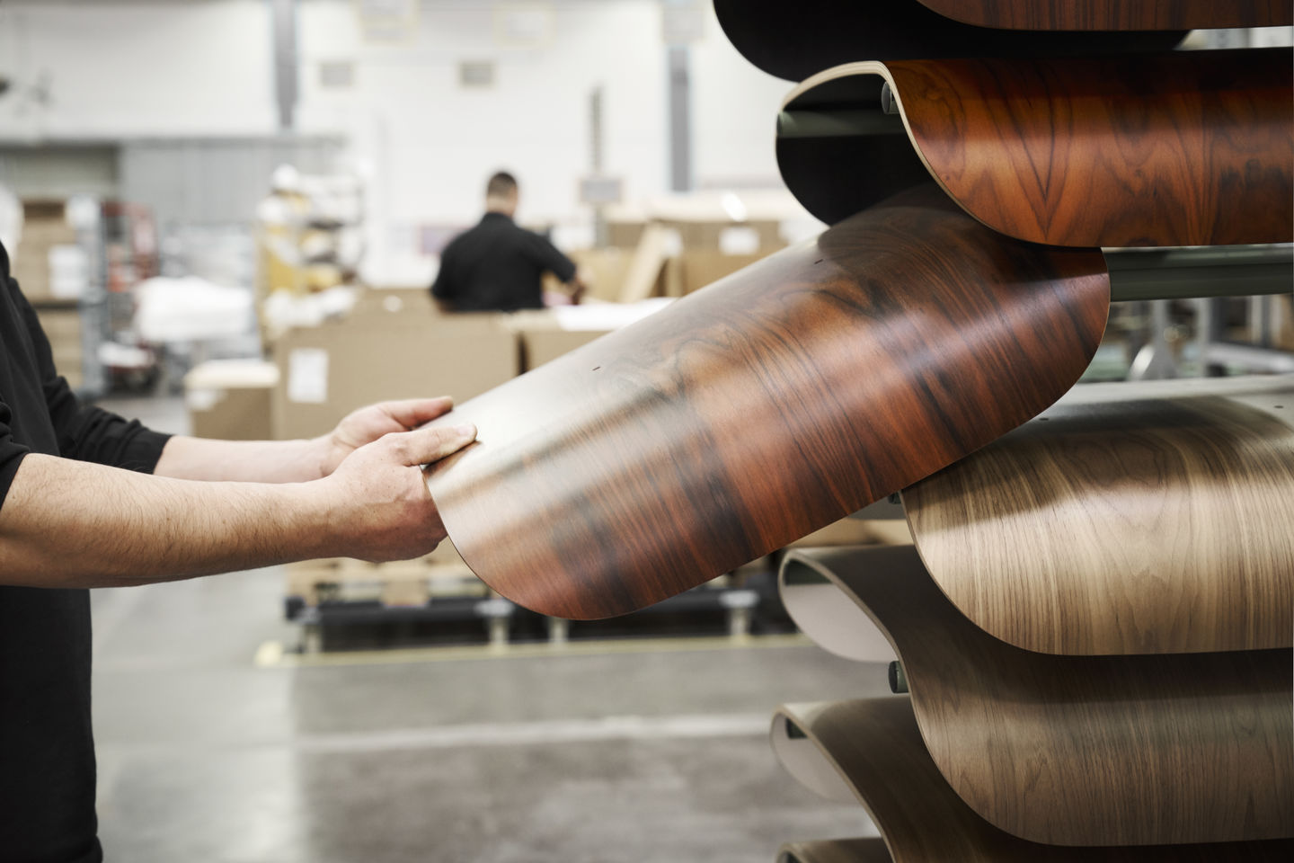 Mann hält eine Holzschale für einen Eames Lounge Chair Sessel in einer Möbelfabrik.