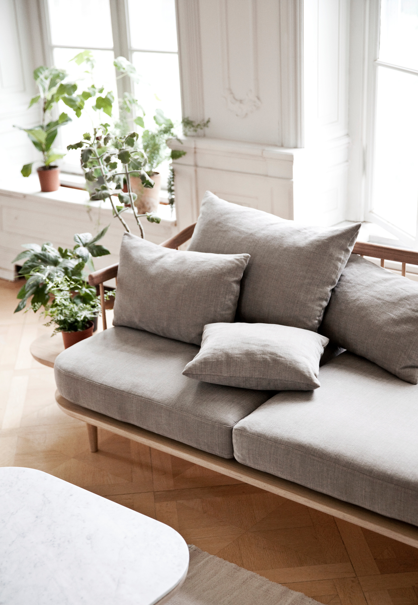 Fly Lounge 2-Sitzer Sofa von AndTradition mit Eichengestell und grauer Polsterung im hellen Wohnraum.