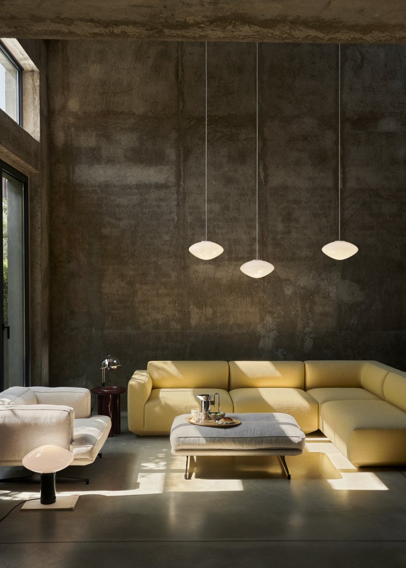 Drei AndTradition Mist Pendelleuchten aus Opalglas über einer gelben Wohnlandschaft in modernem Wohnzimmer.